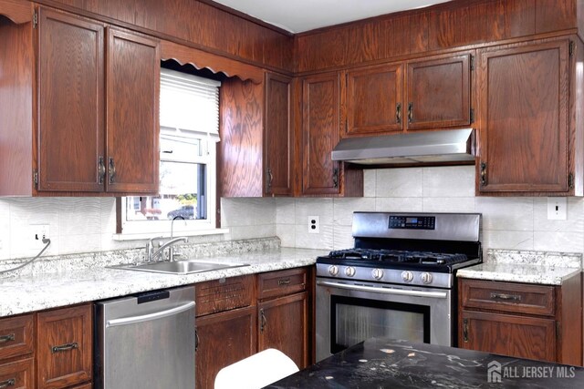 kitchen featuring light stone countertops, decorative backsplash, and stainless steel appliances