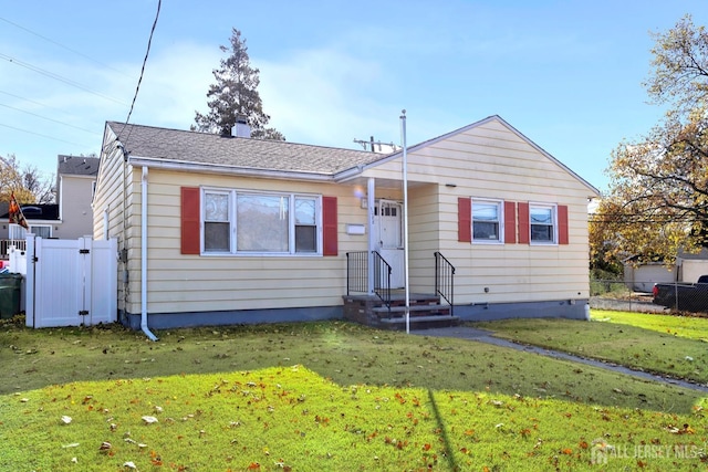 bungalow-style house with fence, roof with shingles, a front yard, and a gate