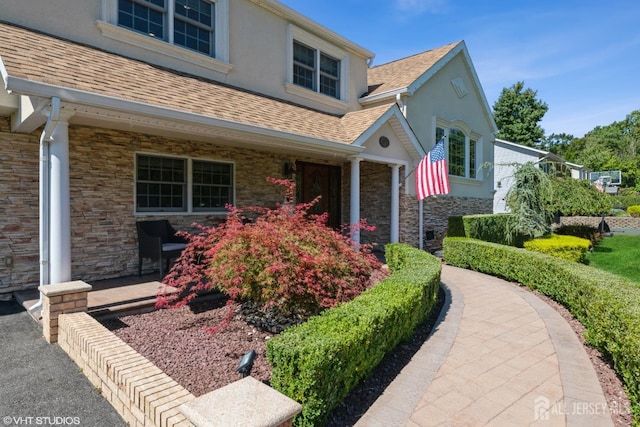 35 Winthrop Dr, Manalapan, NJ 07726 - view of property exterior featuring stone siding, a shingled roof, stucco siding, and covered porch