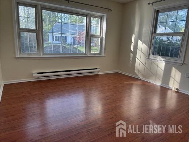 empty room with baseboards, a baseboard radiator, and wood finished floors