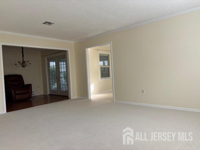 interior space with a healthy amount of sunlight, ornamental molding, a textured ceiling, and visible vents
