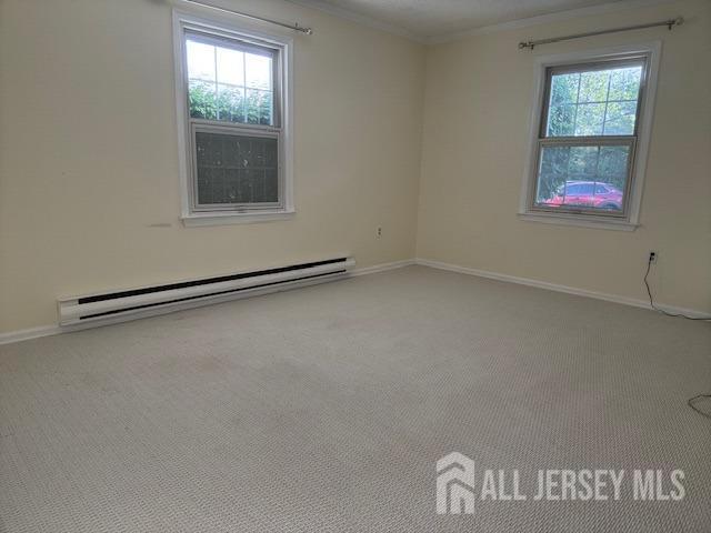 empty room featuring baseboards, a baseboard radiator, ornamental molding, and carpet flooring