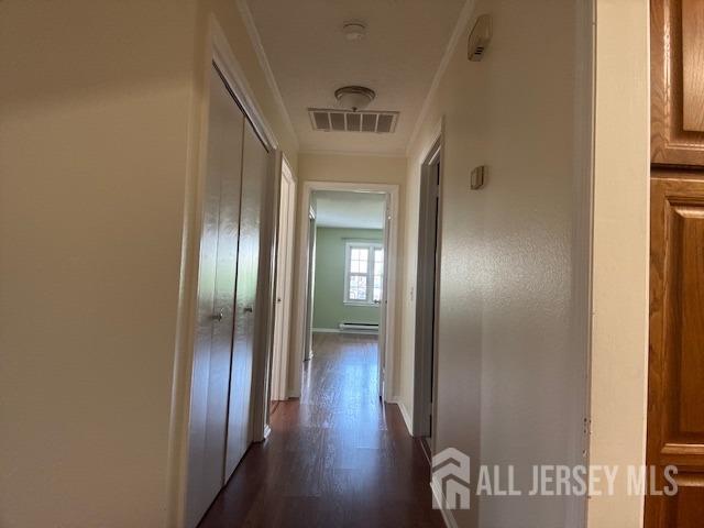 corridor with visible vents, a baseboard radiator, baseboards, and dark wood-type flooring