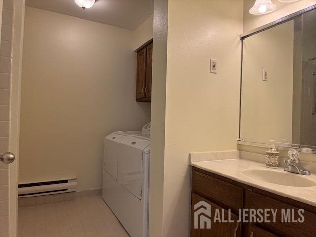 bathroom with washer and dryer, a baseboard heating unit, and vanity