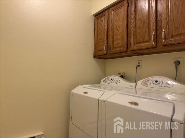 clothes washing area featuring cabinet space and washer and dryer