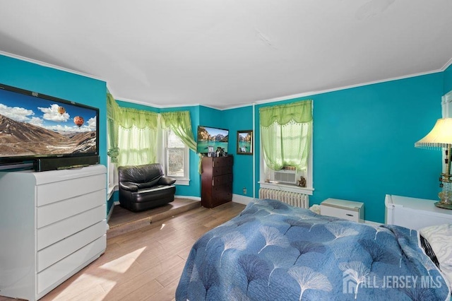 bedroom featuring hardwood / wood-style flooring, crown molding, radiator, and multiple windows