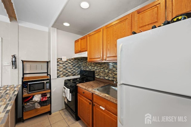 kitchen featuring decorative backsplash, black stove, sink, light tile patterned floors, and white fridge