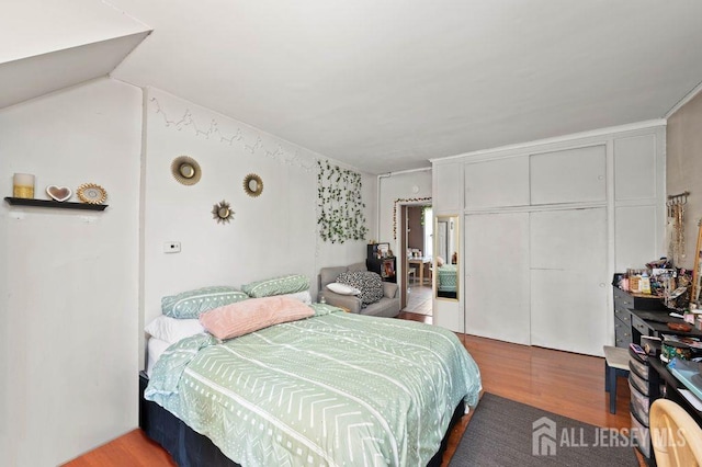 bedroom with hardwood / wood-style flooring, vaulted ceiling, and a closet