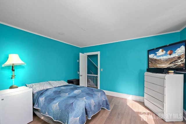 bedroom featuring wood-type flooring and ornamental molding