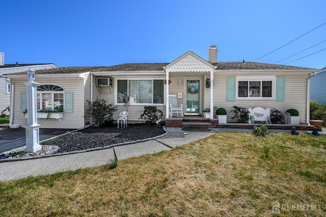 view of front of property featuring a front lawn, a wall mounted AC, and a chimney