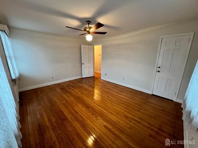 empty room featuring dark wood-type flooring and ceiling fan