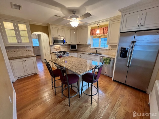 kitchen with sink, stainless steel appliances, a kitchen breakfast bar, a center island, and decorative light fixtures