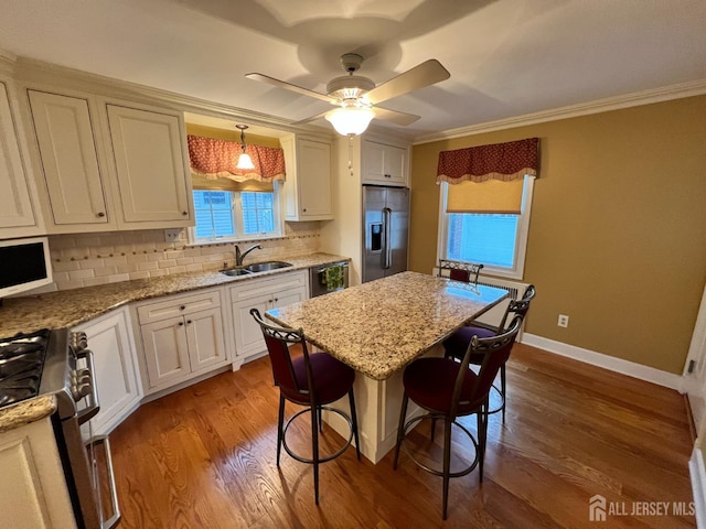 kitchen featuring appliances with stainless steel finishes, decorative light fixtures, sink, a breakfast bar area, and light stone countertops