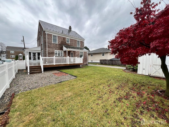 back of house featuring a wooden deck, a storage shed, and a yard