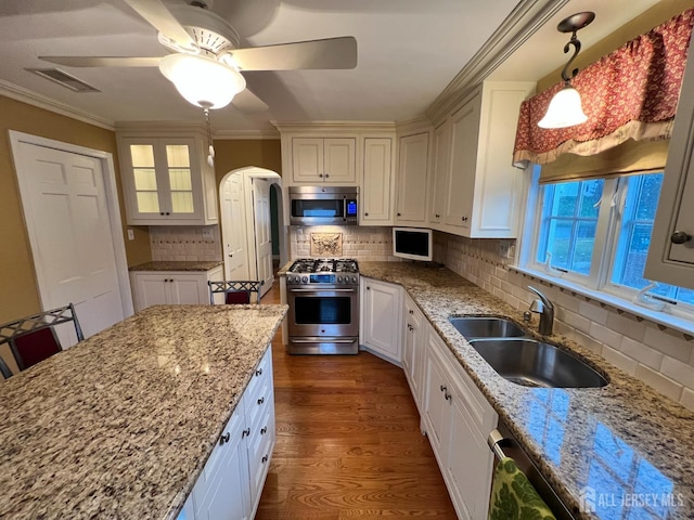 kitchen with sink, backsplash, hanging light fixtures, stainless steel appliances, and light stone countertops