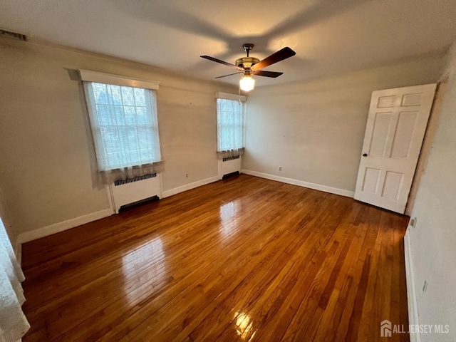 unfurnished room with a wealth of natural light, radiator heating unit, and ceiling fan