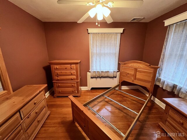 bedroom featuring ceiling fan, radiator heating unit, and hardwood / wood-style floors