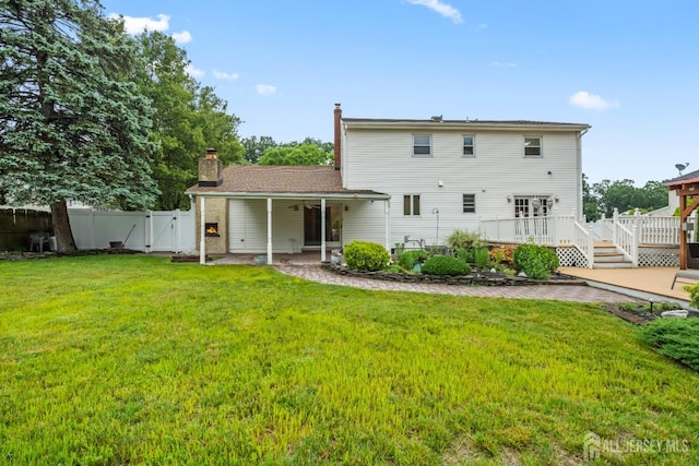 16 London Dr, East Brunswick, NJ 08816 - rear view of house featuring a gate, a wooden deck, a chimney, a ceiling fan, and a patio