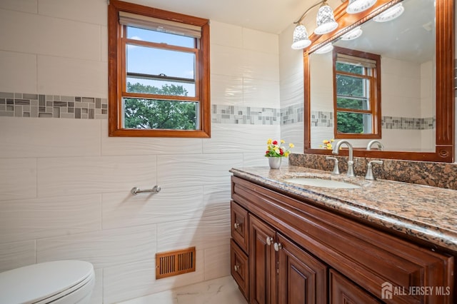 16 London Dr, East Brunswick, NJ 08816 - bathroom with vanity, tile walls, plenty of natural light, and marble look tile flooring