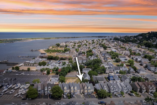 aerial view at dusk featuring a residential view and a water view