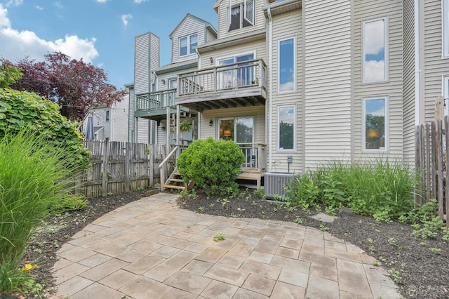 rear view of property featuring central air condition unit, a balcony, fence, and a patio area