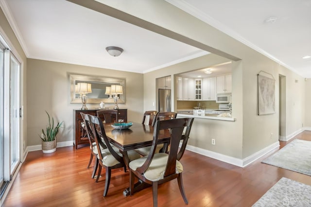 dining room featuring wood finished floors, baseboards, and ornamental molding