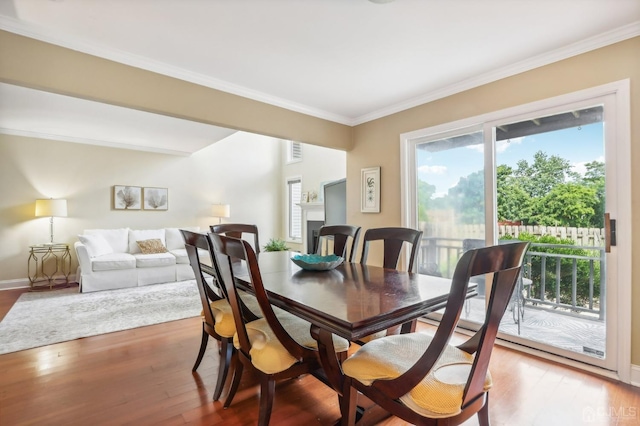 dining space with wood finished floors, ornamental molding, and baseboards