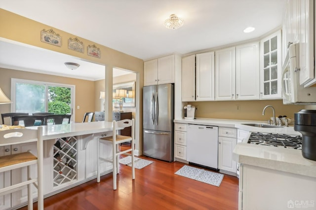 kitchen featuring white appliances, a sink, light countertops, dark wood-style flooring, and glass insert cabinets