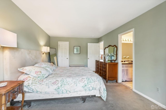 carpeted bedroom featuring connected bathroom and baseboards