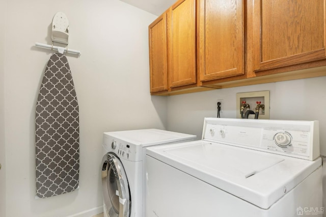 clothes washing area featuring washer and dryer and cabinets