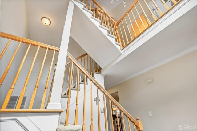 stairs featuring crown molding and a high ceiling