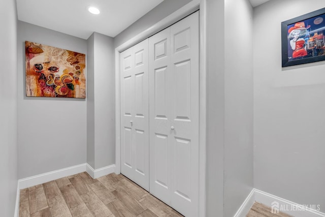 corridor with baseboards, recessed lighting, and light wood finished floors