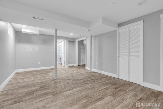 finished below grade area with baseboards, visible vents, and light wood finished floors
