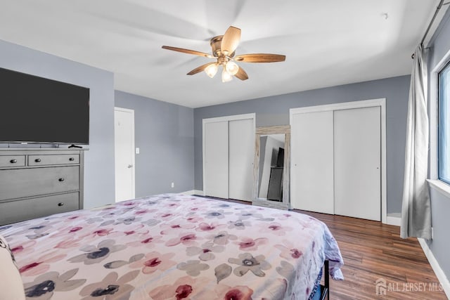 bedroom featuring two closets, a ceiling fan, baseboards, and wood finished floors