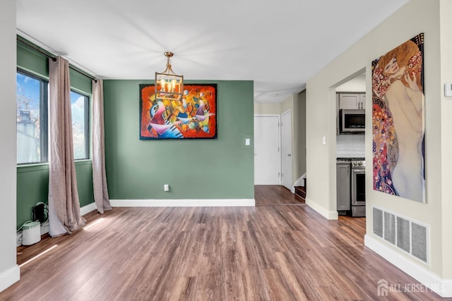 unfurnished dining area with visible vents, baseboards, and wood finished floors