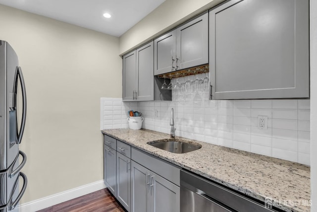 kitchen featuring baseboards, a sink, gray cabinetry, and stainless steel appliances