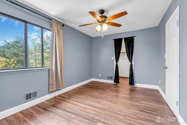 spare room featuring baseboards, ceiling fan, wood finished floors, and visible vents