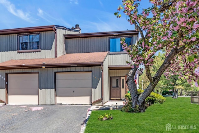 multi unit property featuring driveway, a front yard, and a garage
