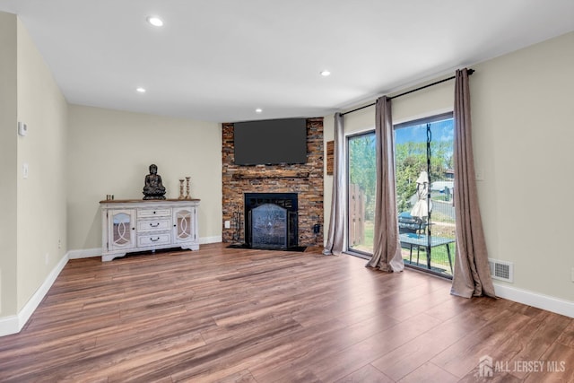 unfurnished living room with a stone fireplace, recessed lighting, baseboards, wood finished floors, and visible vents