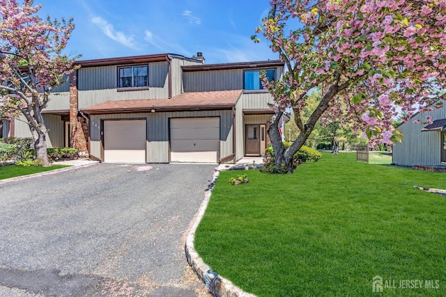 townhome / multi-family property with a garage, gravel driveway, and a front lawn