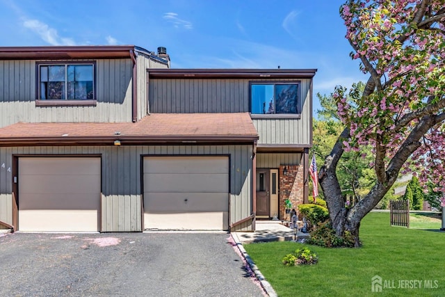 multi unit property with roof with shingles, driveway, and a front yard