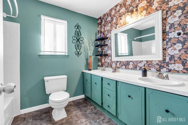 full bathroom featuring a sink, toilet, double vanity, baseboards, and wallpapered walls