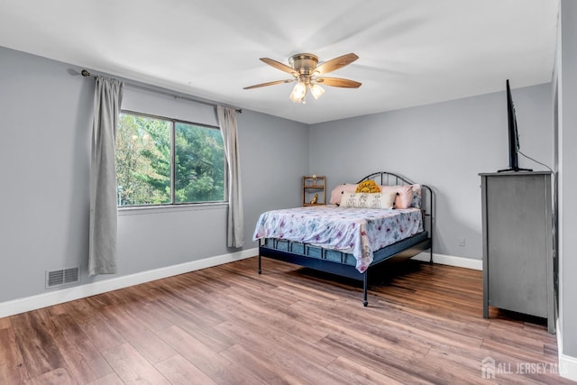 bedroom featuring visible vents, baseboards, and wood finished floors