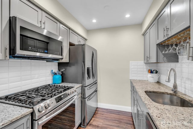 kitchen with baseboards, a sink, gray cabinets, and appliances with stainless steel finishes