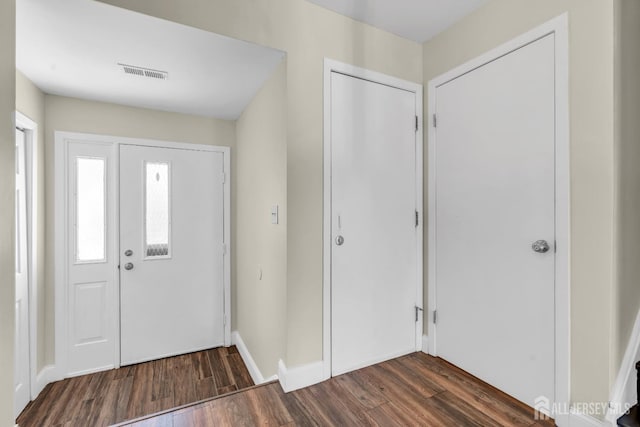 foyer entrance featuring baseboards, dark wood-type flooring, and visible vents