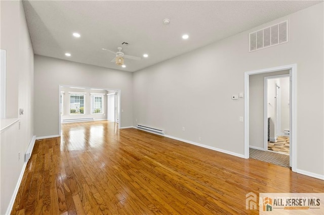 unfurnished living room featuring wood finished floors, visible vents, a baseboard radiator, and baseboard heating