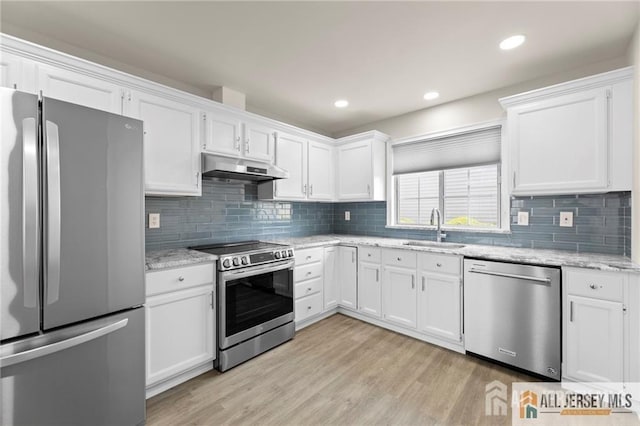 kitchen with light wood-style flooring, under cabinet range hood, stainless steel appliances, a sink, and white cabinets