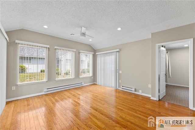 spare room with baseboard heating, a textured ceiling, vaulted ceiling, and hardwood / wood-style flooring