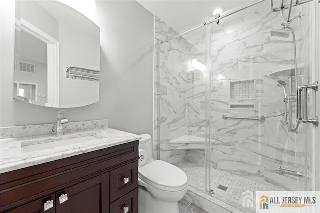 bathroom featuring toilet, a marble finish shower, visible vents, and vanity