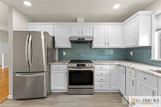 kitchen with white cabinets, under cabinet range hood, stainless steel appliances, and light wood-style floors